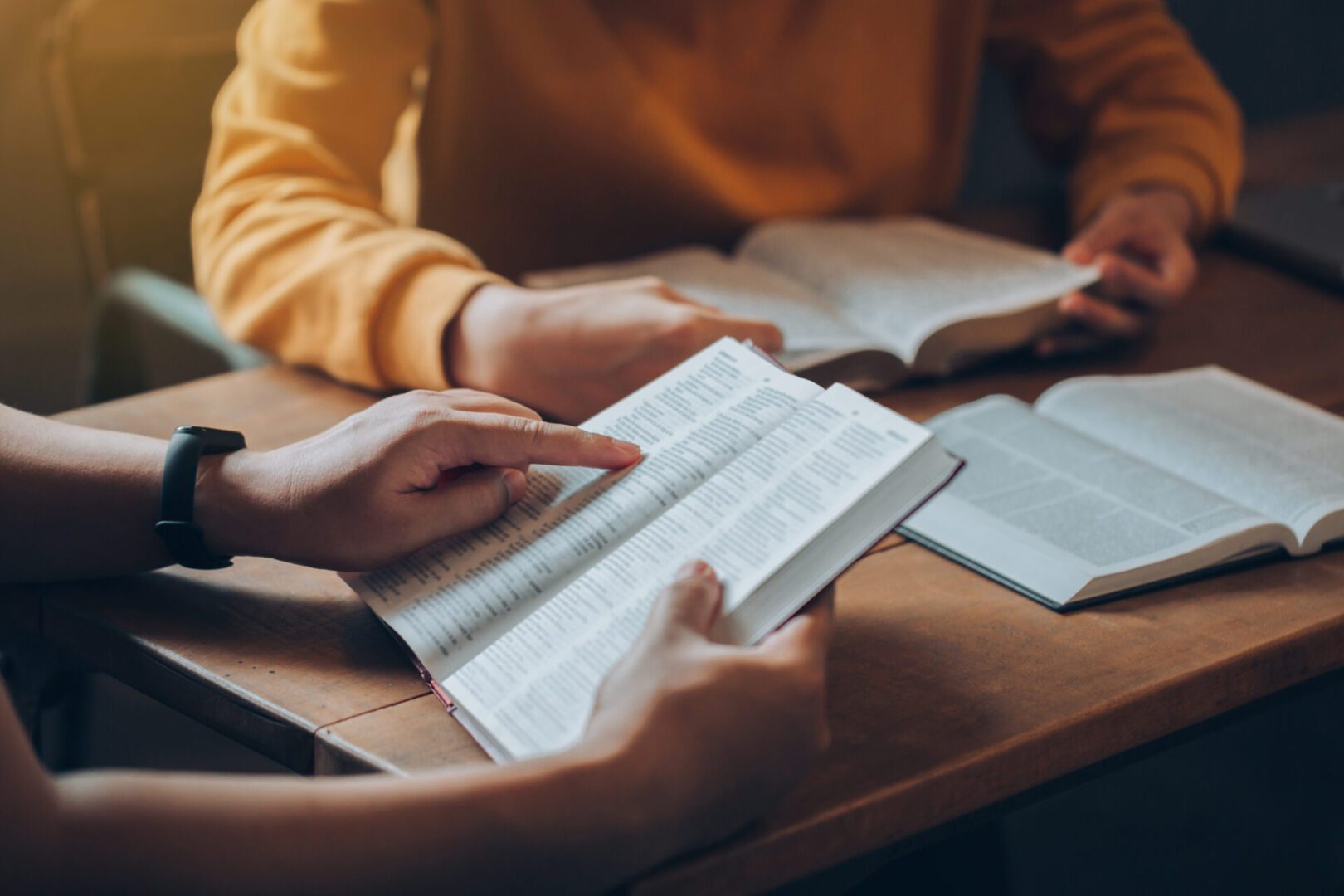 People studying books at a wooden table.